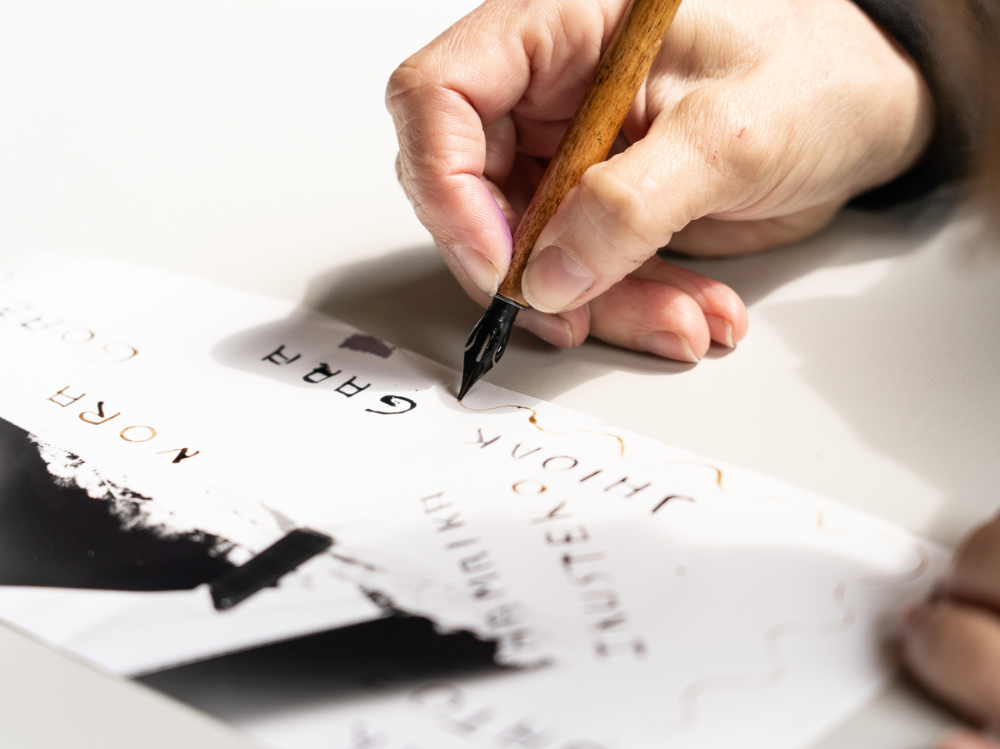 Una mano que escribe en un papel con una pluma.